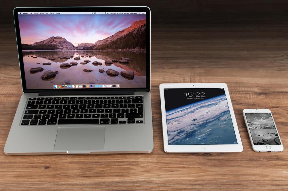 laptop, tablet, and phone on a wooden desk