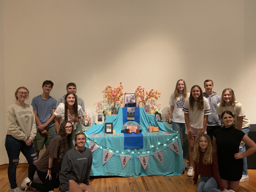 Spanish II students stand with their art exhibit.